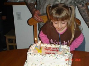 Jason standing behind Hailley while she blows out candles